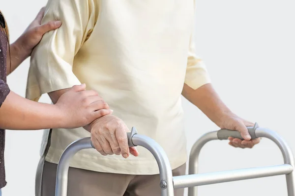 Пожилая женщина, использующая ходунки с сиделкой — стоковое фото