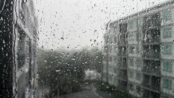 Regentropfen auf einer Fensterscheibe, Gebäude im Hintergrund. — Stockvideo