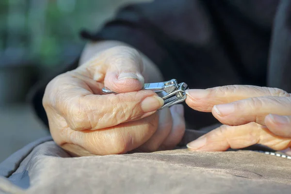 Äldre kvinna klippa naglar — Stockfoto