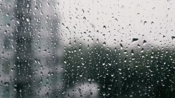 Gouttes de pluie sur une vitre, bâtiments en arrière-plan .