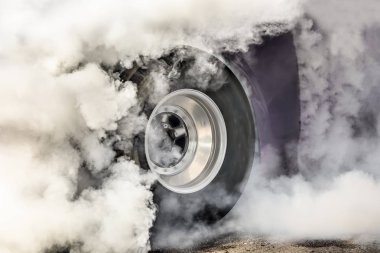 Drag racing car burns rubber off its tires in preparation for the race clipart