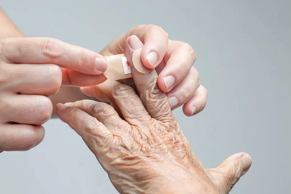 Infermiera mettendo benda adesiva sulla mano della donna anziana — Foto Stock