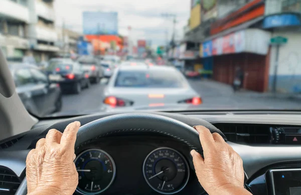 Mujer mayor conduciendo un coche en un atasco de tráfico — Foto de Stock