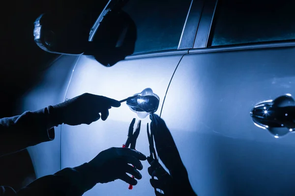 Car thief using a tool to break into a car — Stock Photo, Image