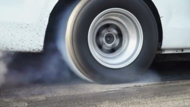 Sürüklenen yarış arabası yarışa hazırlanırken lastiklerini yakıyor.