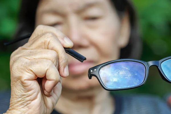 Elderly asian woman repair broken glasses — Stock Photo, Image