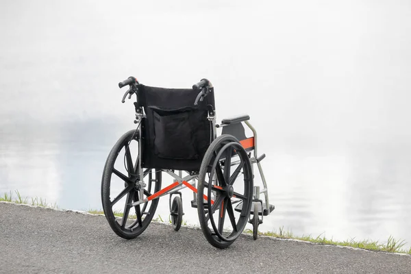 Cadeira de rodas vazia no lago — Fotografia de Stock