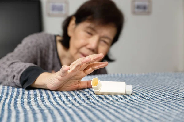 Mujer mayor asfixiándose y sosteniendo un aerosol de asma — Foto de Stock