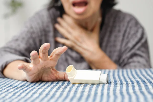 Mujer mayor asfixiándose y sosteniendo un aerosol de asma en casa . —  Fotos de Stock