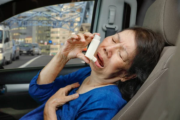 Mujer mayor ahogándose y sosteniendo un spray de asma dentro del coche en el camino — Foto de Stock