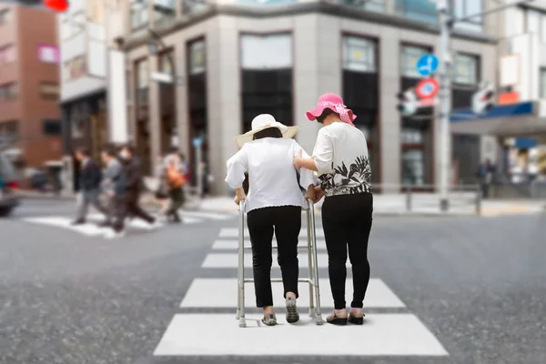 Fille prendre soin femme âgée marche à travers la rue dans le centre-ville — Photo