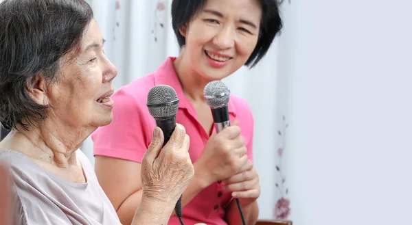 Mulher idosa canta uma canção com filha em casa . — Fotografia de Stock