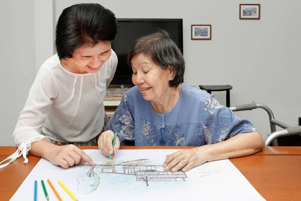 Bejaarde vrouw schilderij kleur op haar tekening met dochter, hobby thuis — Stockfoto