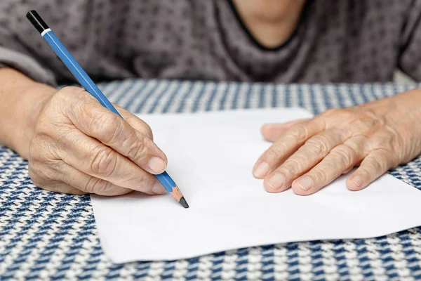 Äldre kvinna skriver på blankt papper Stockfoto