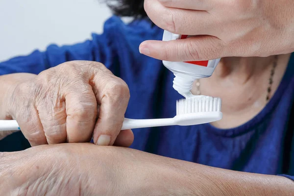 Mulher idosa asiática tentando usar escova de dentes, tremor de mão. Saúde dentária — Fotografia de Stock