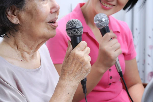 老年妇女和女儿在家里唱一首歌. — 图库照片