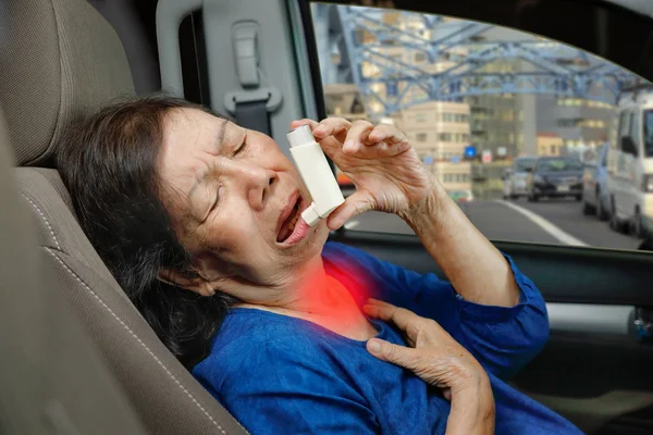 Mujer anciana ahogándose y sosteniendo un spray de asma dentro del coche —  Fotos de Stock