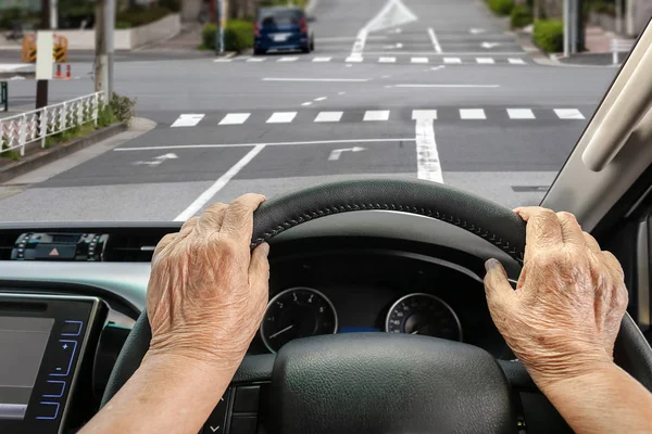 Mujer mayor conduciendo un coche en la calle en la ciudad . — Foto de Stock