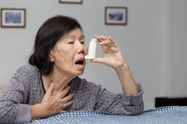 Boğulma ve bir astım spreyi tutan yaşlı kadın 