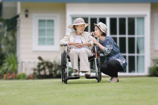 高齢の女性が娘と一緒に裏庭で車椅子でリラックスします。 — ストック写真