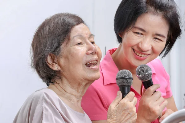 Bejaarde vrouw zingen een lied met dochter thuis. — Stockfoto