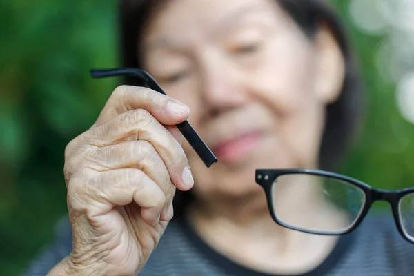 Yaşlı Asyalı kadın tamir kırık gözlük — Stok fotoğraf