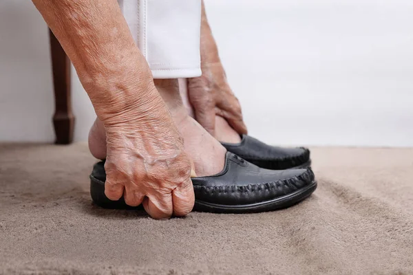 Bejaarde vrouw schoenen zetten — Stockfoto