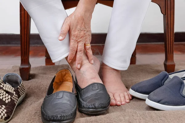 Mujer mayor que se pone los zapatos pies equivocados — Foto de Stock