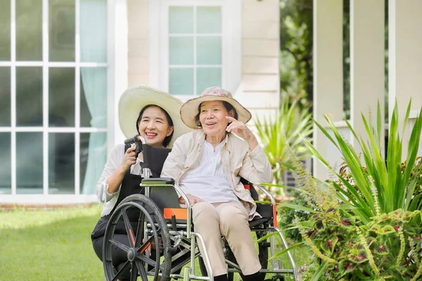 Mujer mayor relajarse en silla de ruedas en el patio trasero con su hija — Foto de Stock