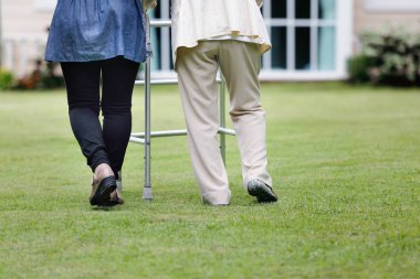 Yaşlı bir kadın kızıyla arka bahçede yürüyor.