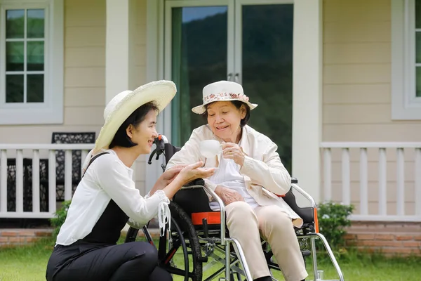 Femme âgée se détendre en fauteuil roulant dans la cour arrière avec sa fille — Photo