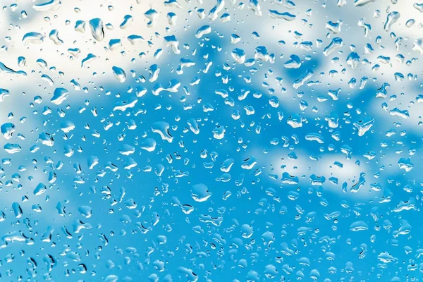 Krople deszczu w dół szyba błękitne niebo dla tła — Zdjęcie stockowe