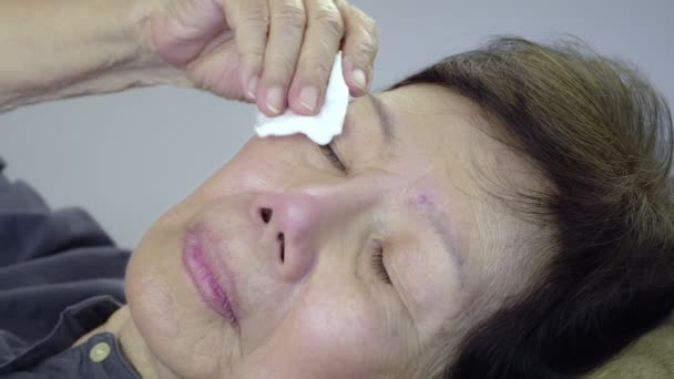 Femme âgée utiliser coton pad nettoyer les yeux sur le lit — Video