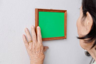 Yaşlı kadın bir anılar fotoğrafa duvara bakarak