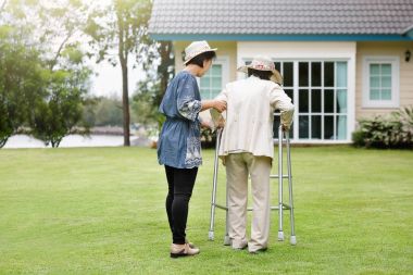 Fizik tedavi daugh ile arka bahçede yürüyen yaşlı kadın