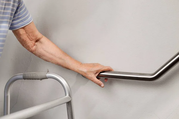 Elderly woman holding on handrail for safety walk steps — Stock Photo, Image