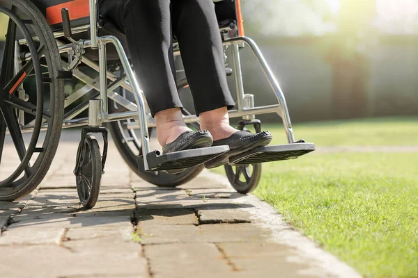 Starsza kobieta, spuchnięte nogi na wózku inwalidzkim na podwórku — Zdjęcie stockowe