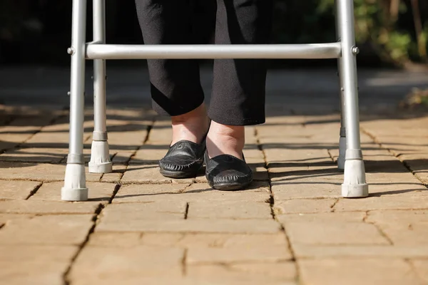 Elderly woman using walker in backyard — Stock Photo, Image