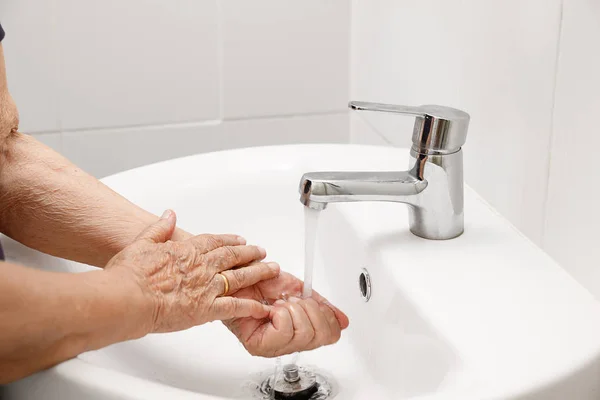 Mujer mayor se lava la mano en el baño — Foto de Stock