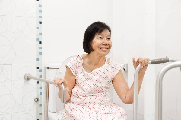 Seniorin hält sich in Toilette am Geländer fest. — Stockfoto