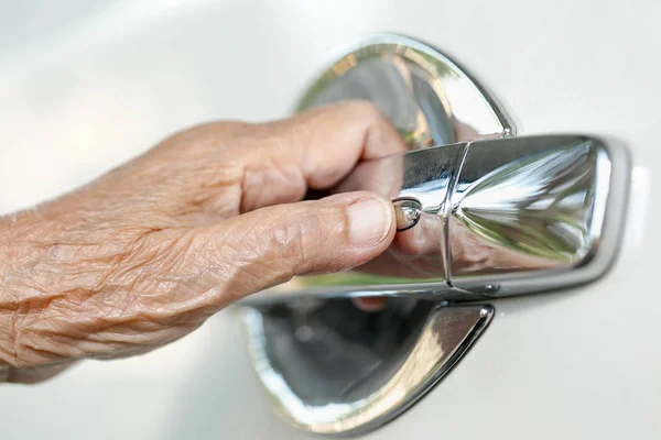 Starsza kobieta ręcznie otwierając drzwi samochodu — Zdjęcie stockowe