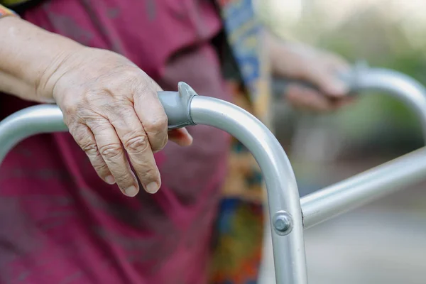 Elderly woman using a walker in backyard — Stock Photo, Image