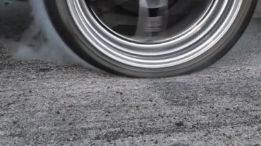 Sürüklenen yarış arabası yarışa hazırlanırken lastiklerini yakıyor.