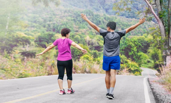 Asiatiska medelålders par stretching muskler innan jogging i parken — Stockfoto