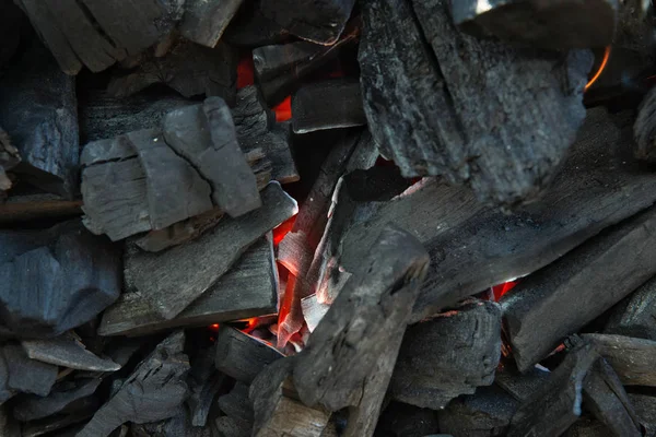 El primer plano del carbón está empezando a quemarse en la parrilla de la cocina. Carbón caliente y llama con humo. —  Fotos de Stock