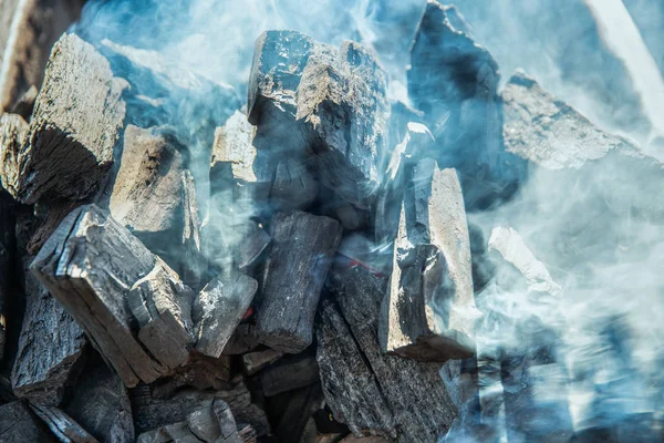 In Großaufnahme beginnt Holzkohle im Küchengrill zu brennen. Heiße Kohle und Flamme mit Rauch. — Stockfoto