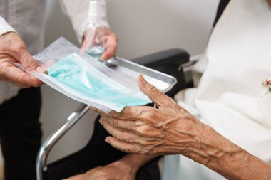 Yaşlı kadın, Coronavirus covid-19 'dan korunmak için bakıcıdan bir maske alır.