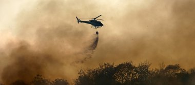 Helikopter orman yangınına su döküyor.