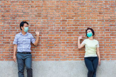 Maske takan Asyalı orta yaşlı insanlar COVID-19 'un yayılmasını önlemek için sosyal mesafeyi koruyorlar.