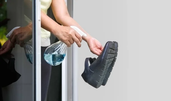 女人在进入一家受Covid 19感染的房子之前 脱掉鞋子 用酒精清洗干净 — 图库照片